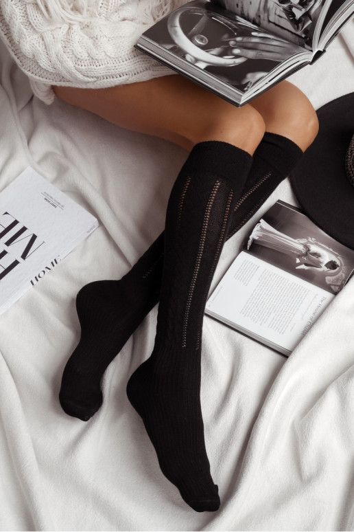 Juodos moteriškos ažūrinės kojinės ant kelių